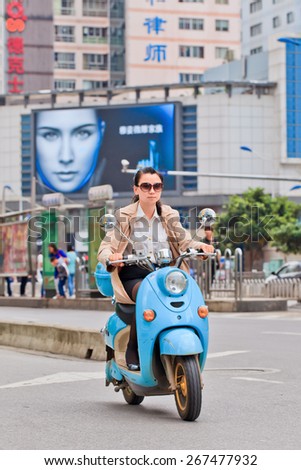 KUNMING-JULY 3, 2014. Girl on an e-bike. An estimated 200 million Chinese now use e-bikes, 1,000-fold increase from 15 years ago. About 90 percent of world\'s e-bikes were sold in China in 2012.
