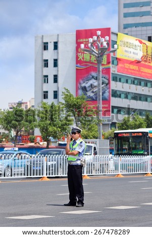 KUNMING-JULY 5, 2014. Police officer with traffic jam on background. China has significantly stepped up security measures, what country\'s state media described as an escalation of anti-terror efforts