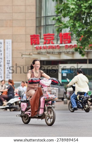 NANJING-MAY 25-2014. Middle aged woman on e-bike. An estimated 200 million Chinese now use e-bikes, 1,000-fold increase from 15 years ago. About 90 % of world\'s e-bikes were sold in China in 2012.