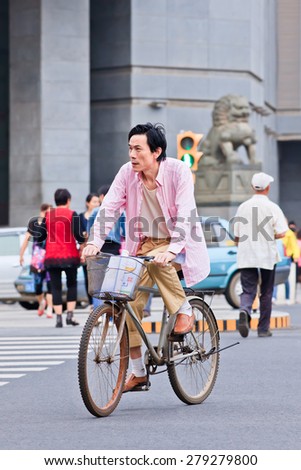 KUNMING-JUNE 30, 2014. Middle aged man cycles in city center. With a population of 1,342,700,000, 500,000,000 bicycles and 37.2 cyclists China is still the number one bicycle country in the world.