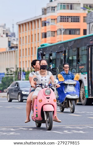 KUNMING-JUNE 30, 2014. Girl with mouth cap on e-bike. An increasing number of Chinese citizens wear breath protection, only eight out of China\'s 74 biggest cities passed 2014 air quality standards.