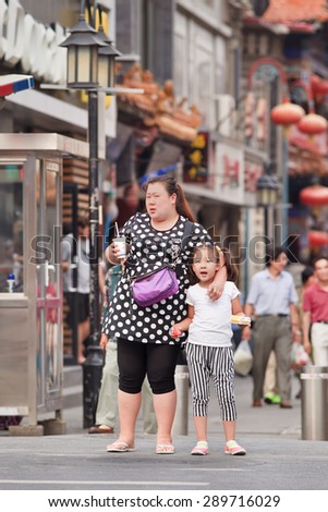 BEIJING, CHINA -JUNE 9, 2015. Overweight woman with a child. China\'s obesity rate has skyrocketed over the last three decades, resulting in 46 million obese Chinese adults and 300 million who are overweight.