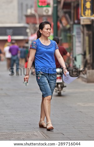 BEIJING, CHINA -JUNE 9, 2015. Middle-aged woman in shopping street. Lives of women in China have significantly changed after government made great efforts towards gender equality in a male-dominated society