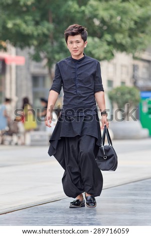 BEIJING, CHINA -JUNE 9, 2015. Fashionable young man in city center. First generation one-child policy consumers have opposite shopping habits from parents. They barely save and spend income rather on fashion.