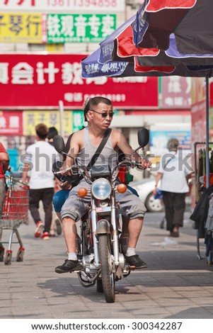 BEIJING-JULY 24, 2015. Couple on a Lifan motorcycle. Lifan is a privately owned Chinese motorcycle and automobile manufacturer in Chongqing founded in 1992, it began manufacture automobiles in 2005.