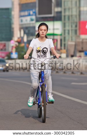 BEIJING-JULY 24, 2015. Young girl rides a public share bicycle. Bicycle sharing allow to hire on a very short term basis, it is a very popular transport mode among commuters in major Chinese cities.