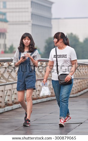 BEIJING-JULY 27, 2015. Skinny and fat Chinese girl on pedestrian bridge. China\'s obesity rate has skyrocketed over last decades, resulting in 46 million obese Chinese adults and 300 million overweight