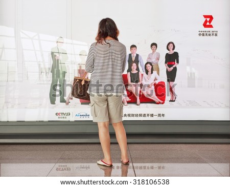 BEIJING-AUG. 30, 2010. Girl in front of advert. China\'s outdoor advertising market has grown annually more than 23% since 2000, versus 17% for the overall ad market, 14% for TV and 16% for newspapers.
