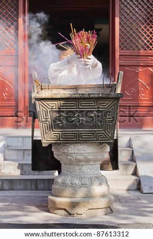 BEIJING - SEPT. 19. Woman throws incense sticks in an altar, Lama Temple Beijing. Incense is widely used in Buddhist ceremonies, ritual purification or meditation. Beijing, Sept. 19, 2007.
