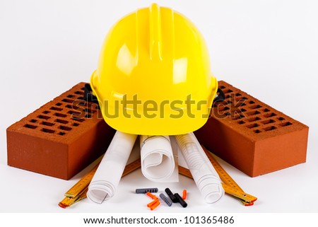 bricks, yellow hard hat, tools and construction plans