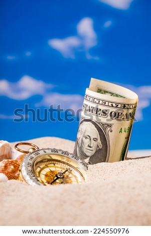 Sea Hedgehog shells  and compass  and dollar money on  sand and blue sky Background
