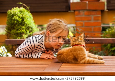 young girl and young cat resting on table in the garden