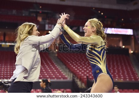 COLLEGE PARK, MD - JANUARY 9: WVU gymnast Melissa Idell is congratulated by a coach following a strong balance beam performance during a meet January 9, 2015 in College Park, MD.