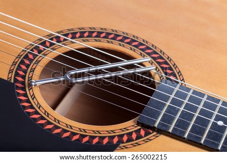Music tuning fork on acoustic guitar metal strings