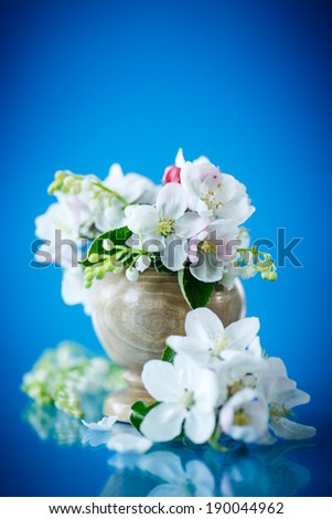 Spring bouquet of lily of the valley and apple blossom on a blue background