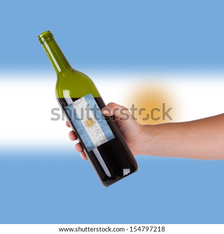 Hand holding a bottle of red wine, label of Argentina, isolated on white,