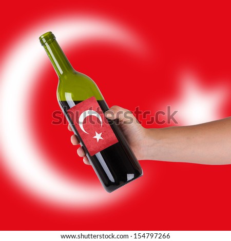 Hand holding a bottle of red wine, label of Turkey, isolated on white,