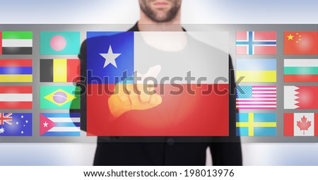 Hand pushing on a touch screen interface, choosing language or country, Chile