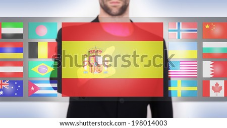 Hand pushing on a touch screen interface, choosing language or country, Spain