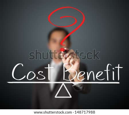 business man writing cost and benefit compare on balance bar