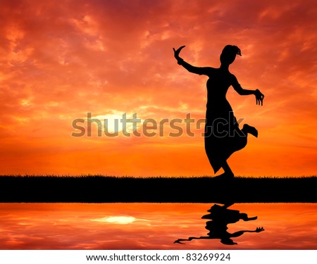 woman performing typical thai dance at sunset silhouetted