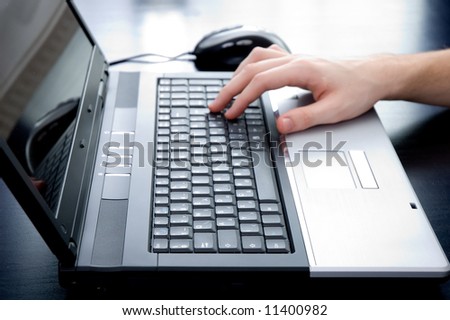 Male hand pushing the enter button on a laptop keyboard. Hand is out of focus!