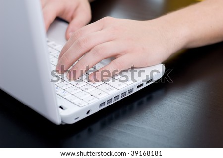Male hands on a notebook keyboard (shallow DOF, focus on left hand)