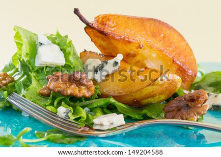 Salad with caramelised pears, walnuts and cheese, on blue plate, with fork