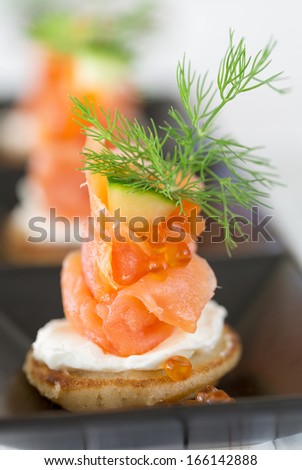 Blini with smoked salmon and sour cream, garnished with dill. Close-up view