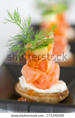 Blini with smoked salmon and sour cream, garnished with dill and caviar. Close-up view