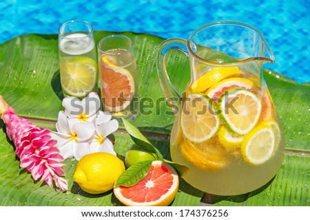 Jug of home made iced lemonade on edge of swimming pool