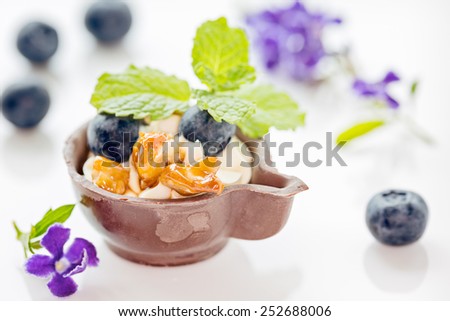 Blueberry and mascarpone dessert in chocolate cup, garnish with caramelized walnuts and mint