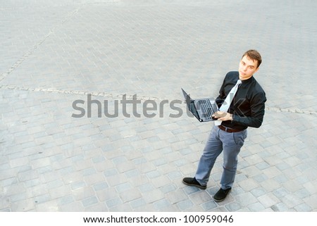 The image of a businessman working on the computer and standing in the middle of the street