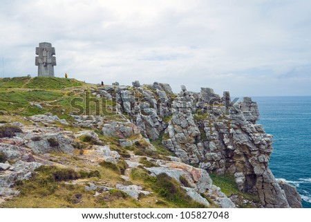 Picture of Pen Hir on which stands a monument in the form of a cross with a stone carved on it the figures of men and women figure in the center dedicated to the Battle of the Atlantic in World War II