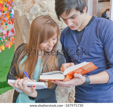 male and female university students standing at the institute and do their homework