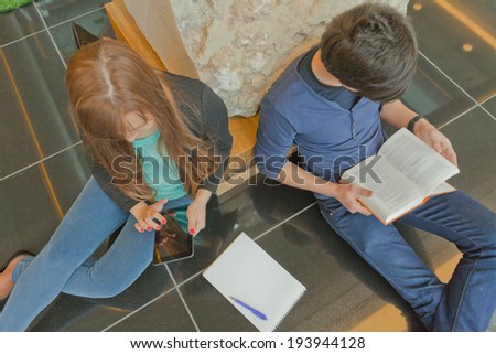 male and female university students sitting on a bench and do their homework