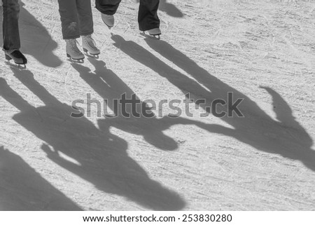 shadow background of family on the ice rink, they hold child\'s by hands