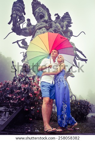 Couple traveling to Asia with umbrellas in bad weather, Balinese Botanical Garden