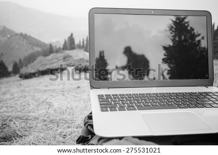 someone uses laptop remotely with 3g or 4g network wireless at mountain, reflection of hiking tourist at monitor, black and white edition