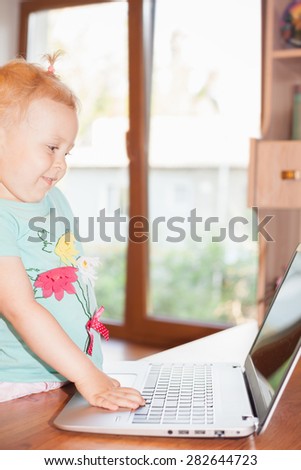 Child using laptop at home. Little girl play some computer game or watching a cartoons