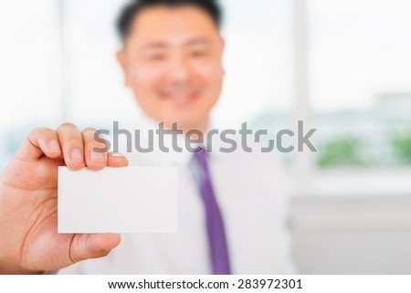 Happy and successful asian businessman gives you a business card or visiting card with a white background on a blank for copy space and any contacts or phone number