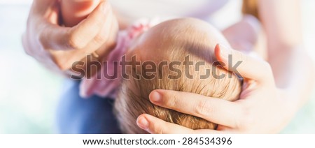 Letterbox format image of mother holding baby head, there is concept or idea of love, family and happiness at the home, like mother caring for newborn.