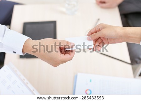 closeup image of successful deal, businessman gives businesswoman a business card or visit card with a white background on a blank for copy space and any contacts or phone number