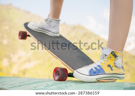 close-up image of teenager doing a trick by skateboard - longboard on a street at the skate park outdoor at mountain. World Day of skateboarding.