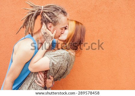 Happy and funny couple kissing at red wall background. Image ready for International, World Kissing Day 6 July or Valentine\'s Day, with copy space for any text or design