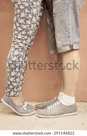 Closeup foot of kissing couple outdoor at street. Shod with same shoes of moccasins or sneakers. International or World Kissing Day 6 July or Valentine\'s Day