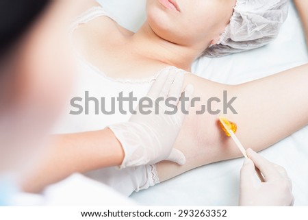 Professional woman at spa beauty salon doing epilation armpits using sugar  - sugaring. You can see her smooth and hair free armpits after hair removal