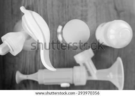 Background of manual and automatic breast pump, baby bottle with milk. Mothers breast milk is most healthy food for newborn baby. Selective focus and black and white edition