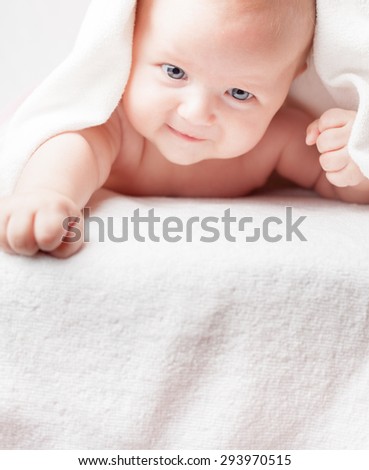 Happy baby after bathing, looking down on copy space or to the camera, with white towels. Concept of purity and freshness as the care of the child and health. Tearless shampoo