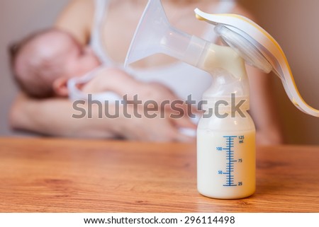 Manual breast pump, mothers breast milk is the most healthy food for newborn baby. Happy mother with baby at background